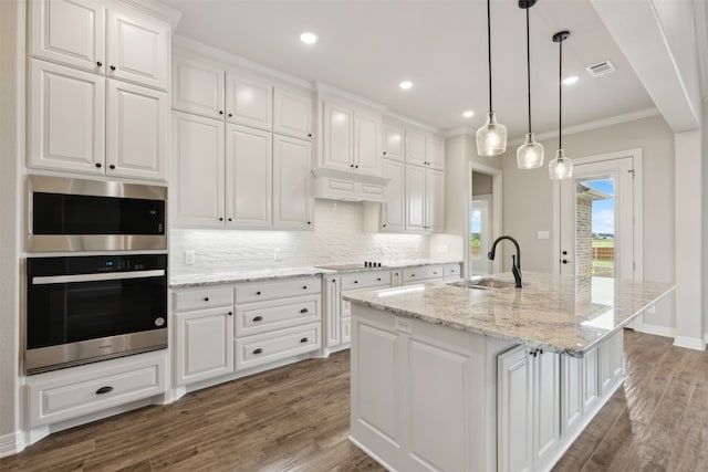 kitchen with white cabinets, a center island with sink, dark wood-type flooring, and sink