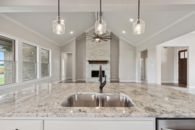 kitchen featuring sink, vaulted ceiling, a fireplace, crown molding, and ceiling fan