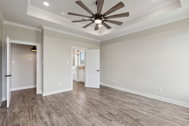 unfurnished bedroom featuring ceiling fan, a raised ceiling, crown molding, and light hardwood / wood-style floors