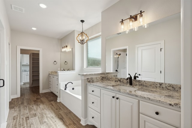 bathroom with wood-type flooring, vanity, and a tub to relax in