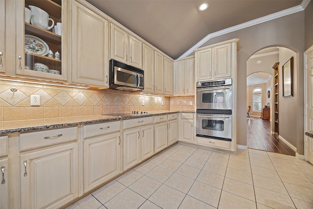 kitchen featuring stainless steel appliances, vaulted ceiling, light tile patterned flooring, and cream cabinetry