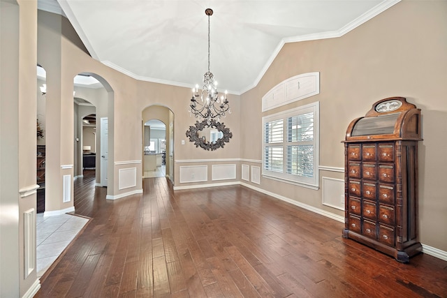 foyer with wood-type flooring, lofted ceiling, crown molding, and an inviting chandelier