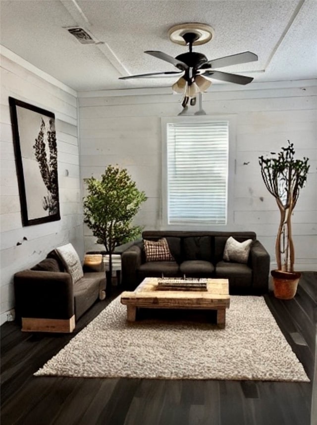 living room featuring a textured ceiling, wood-type flooring, wooden walls, and ceiling fan