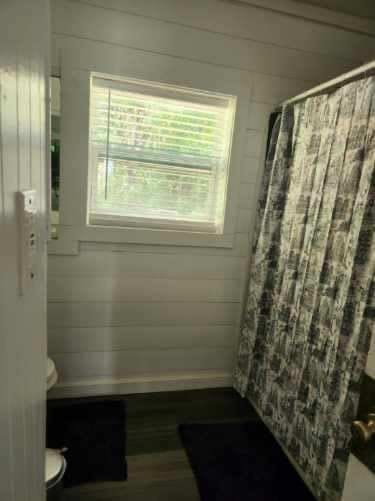 bathroom featuring wooden walls, toilet, and a shower with shower curtain