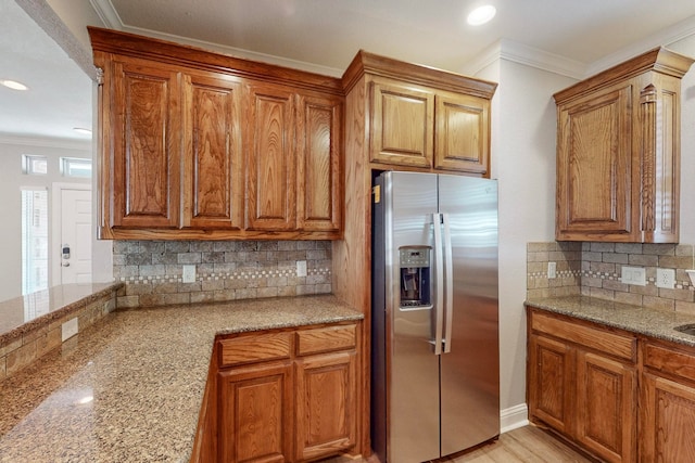 kitchen with light stone counters, tasteful backsplash, stainless steel fridge with ice dispenser, and crown molding