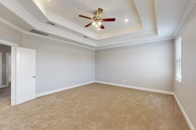 spare room with carpet, a tray ceiling, ornamental molding, and ceiling fan