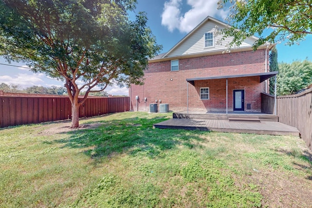 back of house with central AC unit, a wooden deck, and a lawn