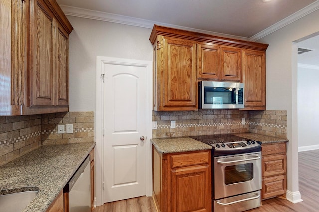 kitchen featuring light stone counters, light hardwood / wood-style flooring, appliances with stainless steel finishes, crown molding, and decorative backsplash