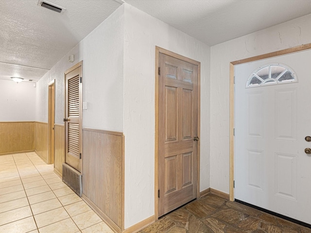 entrance foyer with a textured ceiling and wood walls