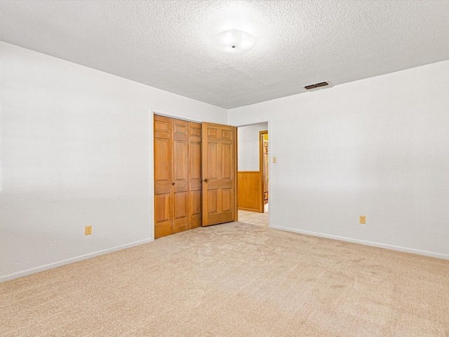 unfurnished bedroom featuring a closet, light carpet, and a textured ceiling