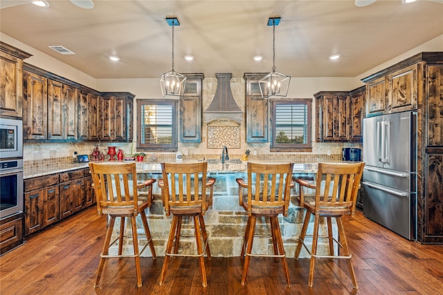 kitchen with a chandelier, a center island, dark wood-type flooring, stainless steel appliances, and a healthy amount of sunlight