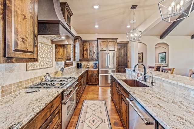 kitchen featuring pendant lighting, tasteful backsplash, stainless steel appliances, a notable chandelier, and light wood-type flooring