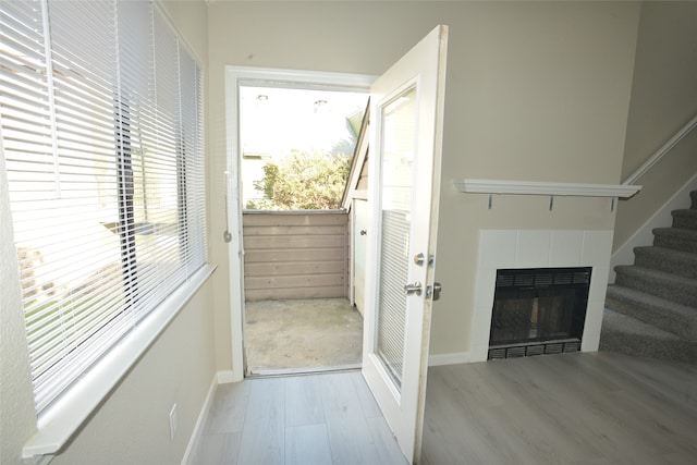 doorway with light hardwood / wood-style floors and a tiled fireplace