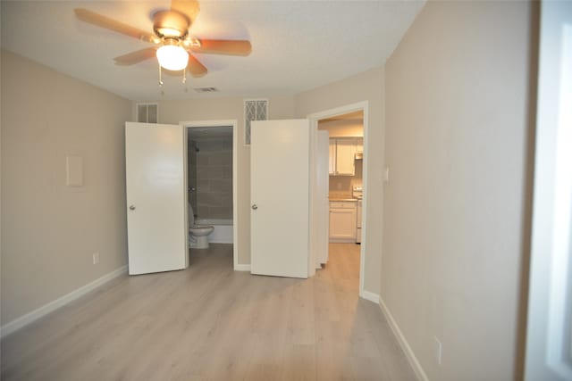 unfurnished bedroom featuring light wood-type flooring, ensuite bath, ceiling fan, and a textured ceiling