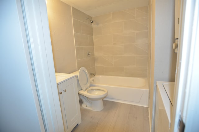 full bathroom featuring wood-type flooring, tiled shower / bath combo, vanity, and toilet