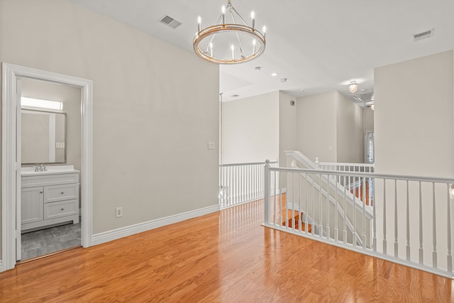 empty room featuring light hardwood / wood-style flooring, a chandelier, and sink