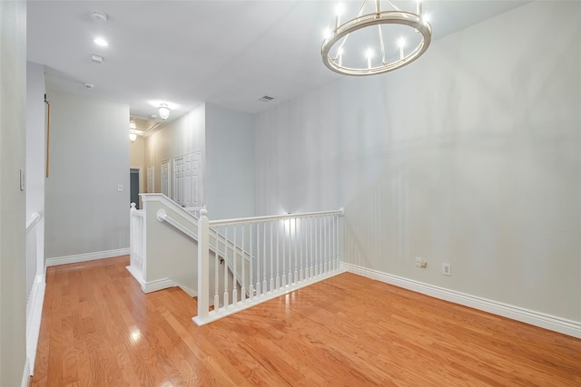 spare room featuring light wood-type flooring and a chandelier