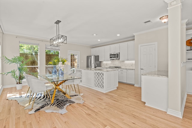 dining area with light wood-type flooring, sink, and crown molding