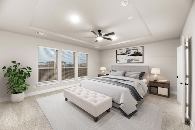 carpeted bedroom with ceiling fan and a tray ceiling