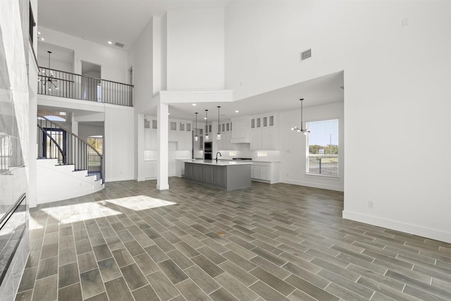 unfurnished living room with an inviting chandelier, sink, and a high ceiling