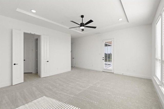 unfurnished bedroom featuring light carpet, a tray ceiling, access to outside, and ceiling fan