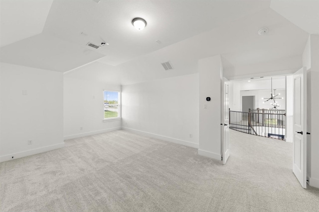 carpeted spare room with vaulted ceiling and a notable chandelier