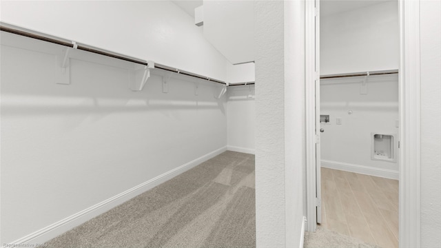 spacious closet featuring light hardwood / wood-style flooring and vaulted ceiling