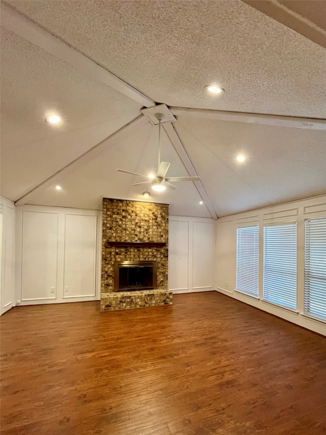 unfurnished living room featuring a textured ceiling, hardwood / wood-style flooring, ceiling fan, and a brick fireplace