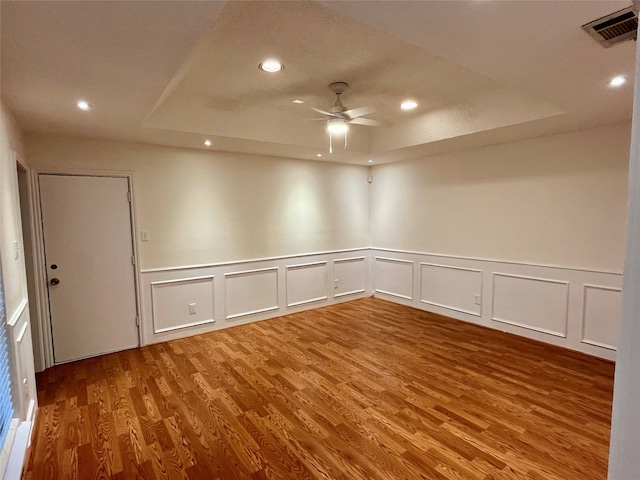 unfurnished room featuring ceiling fan, a raised ceiling, and hardwood / wood-style floors