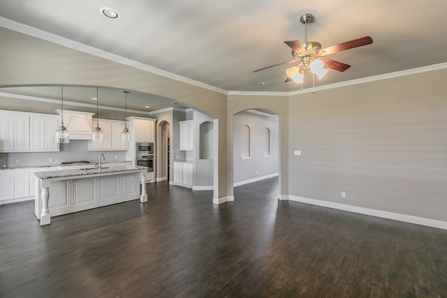 unfurnished living room with ceiling fan, dark hardwood / wood-style floors, sink, and crown molding