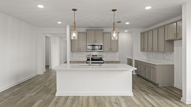 kitchen with appliances with stainless steel finishes, tasteful backsplash, a center island with sink, and sink