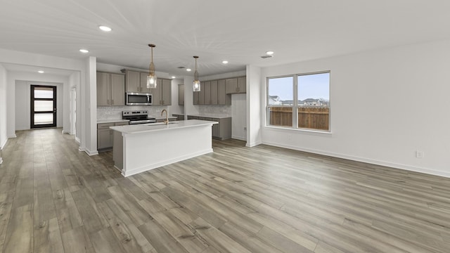 kitchen with sink, gray cabinetry, decorative light fixtures, appliances with stainless steel finishes, and a kitchen island with sink