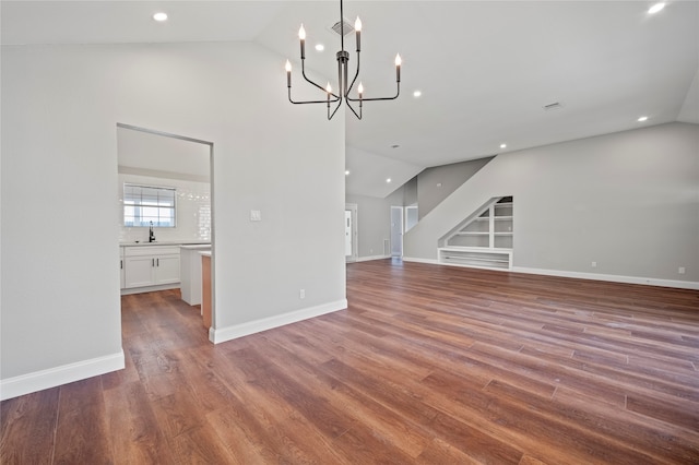 unfurnished living room featuring wood-type flooring, a chandelier, and high vaulted ceiling