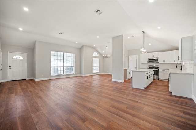 unfurnished living room featuring wood-type flooring, lofted ceiling, sink, and a notable chandelier