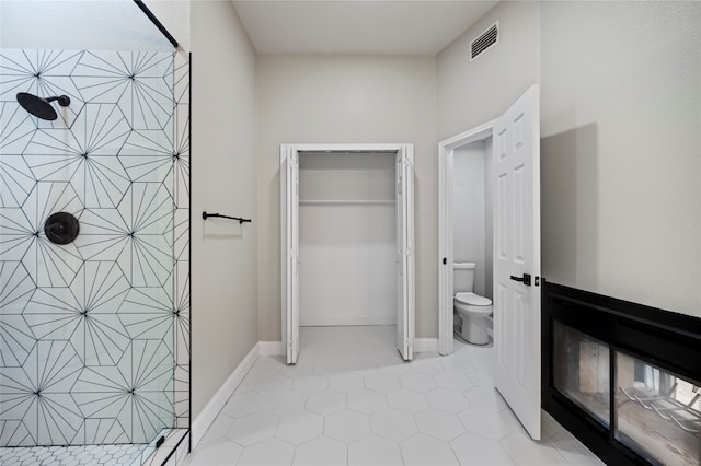 bathroom featuring walk in shower, toilet, and tile patterned floors