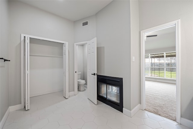 interior space featuring a closet, light colored carpet, and ensuite bathroom