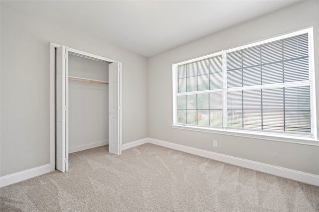 unfurnished bedroom with light carpet and a closet