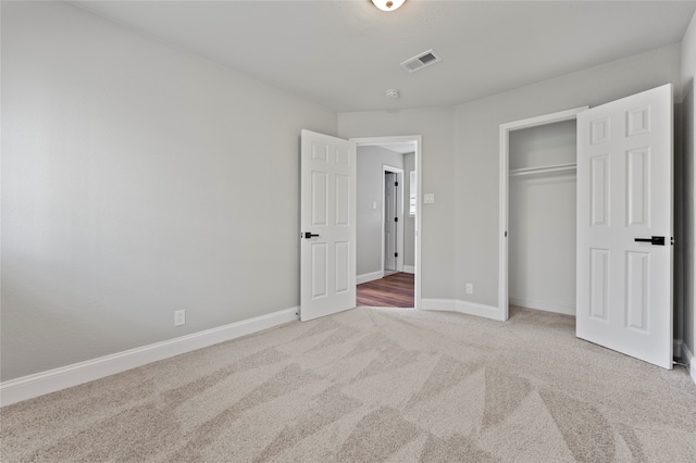 unfurnished bedroom with a closet and light colored carpet