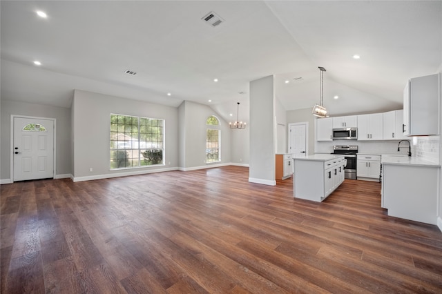 unfurnished living room featuring a notable chandelier, sink, lofted ceiling, and dark wood-type flooring