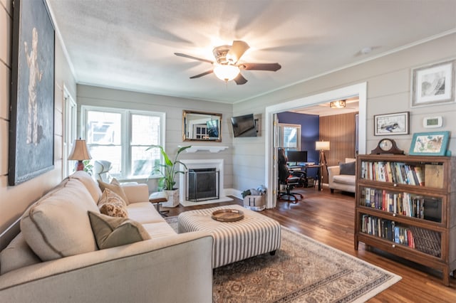 living room featuring hardwood / wood-style floors, ceiling fan, ornamental molding, and a textured ceiling