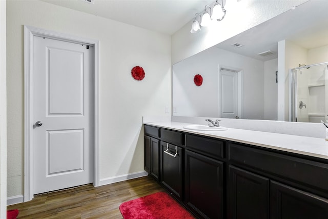 bathroom with hardwood / wood-style flooring, a shower with door, and vanity