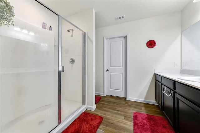 bathroom with walk in shower, vanity, and hardwood / wood-style floors