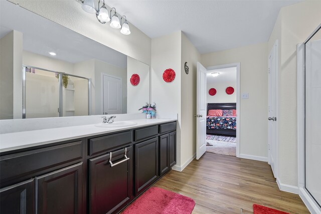 bathroom with vanity, a shower with shower door, and hardwood / wood-style floors