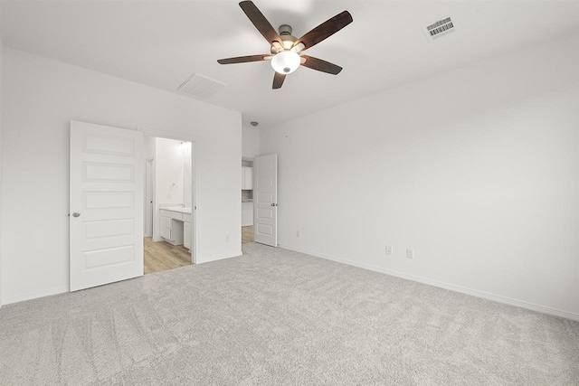 unfurnished bedroom featuring light carpet, ensuite bath, and ceiling fan