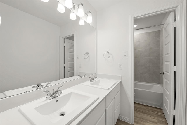 bathroom featuring wood-type flooring, vanity, and tiled shower / bath combo