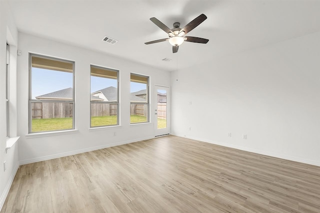 empty room featuring ceiling fan, plenty of natural light, and light wood-type flooring