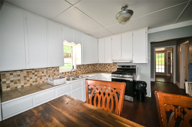 kitchen with decorative backsplash, stainless steel gas range, white cabinets, and sink