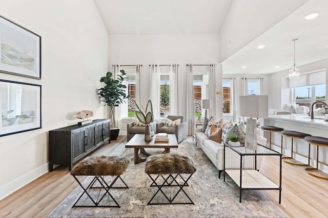 living room featuring lofted ceiling, sink, and light hardwood / wood-style flooring