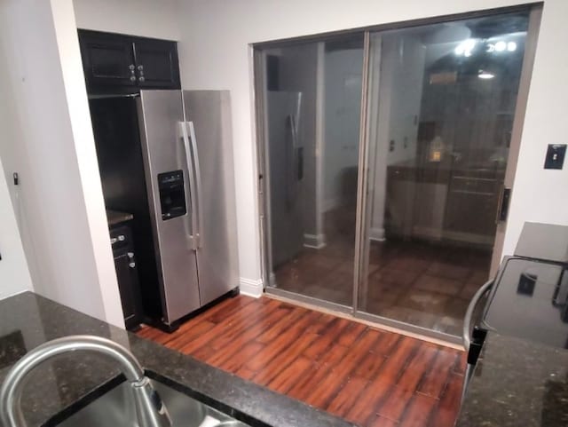 kitchen with stainless steel refrigerator with ice dispenser, dark stone countertops, and dark hardwood / wood-style flooring