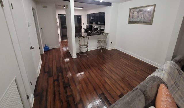 corridor featuring dark wood-type flooring, visible vents, and baseboards